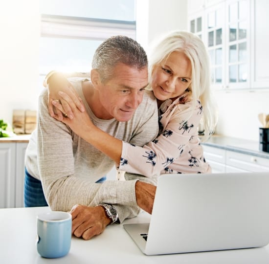 Married couple hugging and looking at laptop