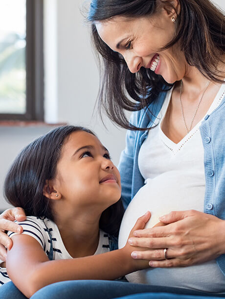 Daughter touching mother's pregnant belly