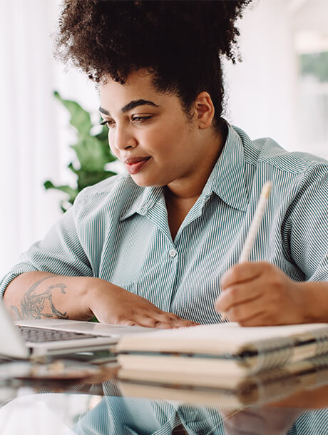 Woman working at laptop and taking notes