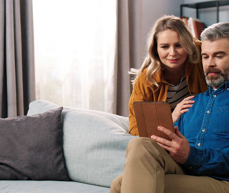 couple on sofa looks at tablet