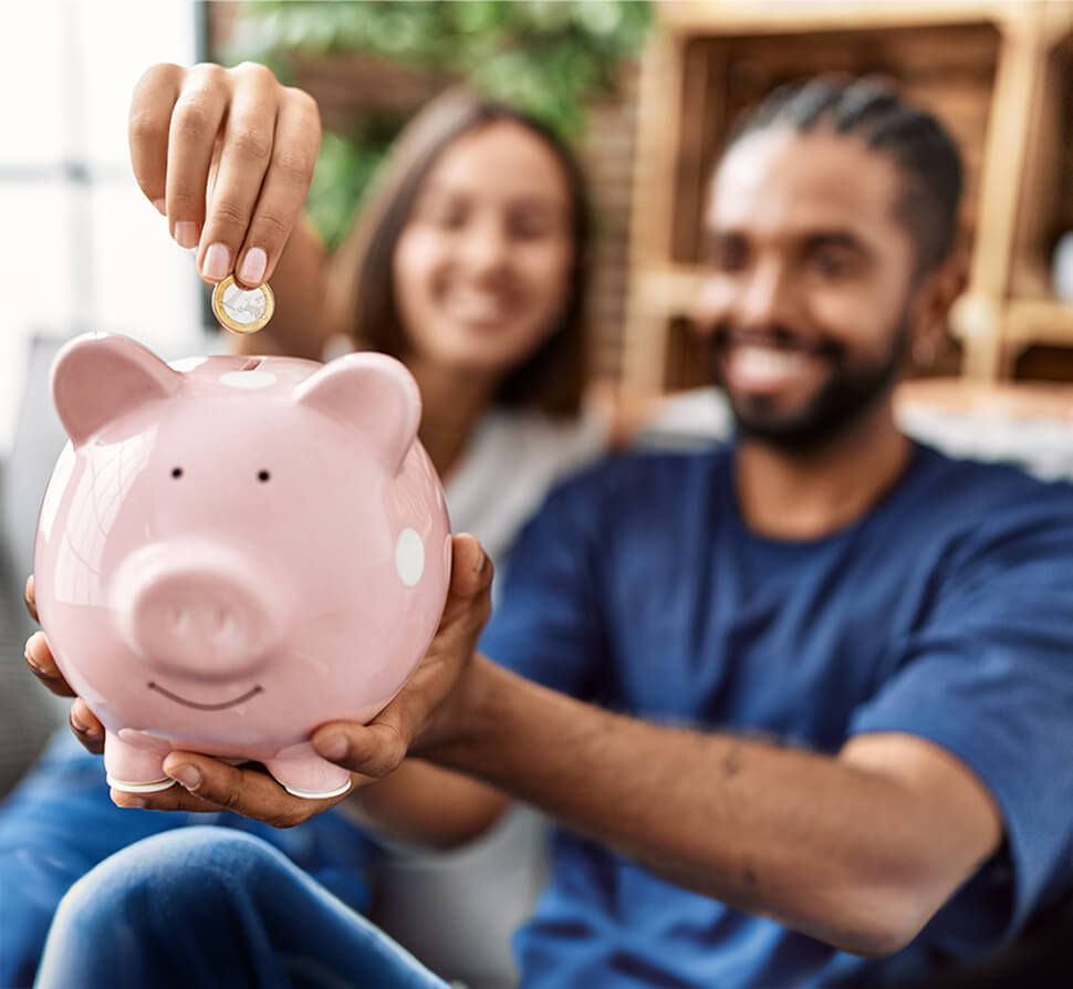 man dropping coin into pink piggie bank. 